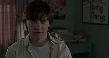 Movie still from “The Ice Storm” (1997), directed by Ang Lee – A young man in a white shirt is posing for a picture; Close Up shot, Over the shoulder angle