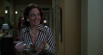 Movie still from “The Ice Storm” (1997), directed by Ang Lee – A smiling woman holding a plate of food in her hands; Medium shot, Low angle