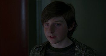 Movie still from “The Ice Storm” (1997), directed by Ang Lee – A young boy with a plaid shirt is looking at the camera; Close Up shot, Over the shoulder angle