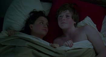 Movie still from “The Ice Storm” (1997), directed by Ang Lee – A woman and a young boy laying in a bed together; Medium shot, Overhead angle