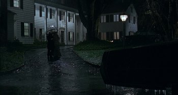 Movie still from “The Ice Storm” (1997), directed by Ang Lee – Two people walking down the street in the rain with an umbrella; Extreme Wide shot, High angle