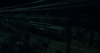 Movie still from “The Ice Storm” (1997), directed by Ang Lee – A train traveling down train tracks at night time; Extreme Wide shot, High angle