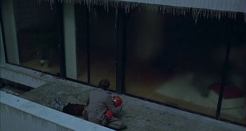 Movie still from “The Ice Storm” (1997), directed by Ang Lee – A man sitting on the ground holding a fire hydrant; Wide shot, Overhead angle