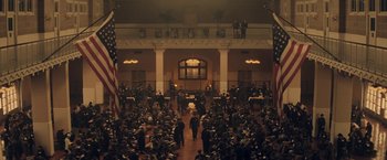 Movie still from “The Immigrant” (2013), directed by James Gray – A crowd of people in an auditorium with a large american flag on the wall; Extreme Wide shot, High angle