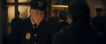 Movie still from “The Immigrant” (2013), directed by James Gray – A man wearing a hat and glasses in front of another man in a suit; Close Up shot, Over the shoulder angle