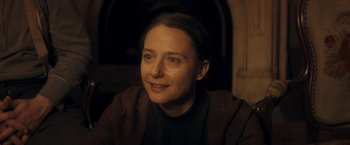 Movie still from “The Immigrant” (2013), directed by James Gray – A woman sitting in front of a fire place smiling for the camera; Close Up shot, Over the shoulder angle