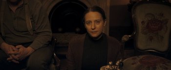 Movie still from “The Immigrant” (2013), directed by James Gray – A woman is sitting in front of a fire place; Medium shot, Over the shoulder angle