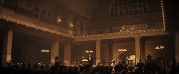 Movie still from “The Immigrant” (2013), directed by James Gray – A man in a suit and tie standing in front of an audience; Extreme Wide shot, High angle