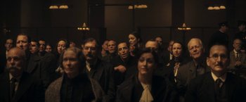 Movie still from “The Immigrant” (2013), directed by James Gray – A group of people standing in a dark room; Medium shot, High angle
