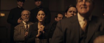 Movie still from “The Immigrant” (2013), directed by James Gray – A group of people sitting in a dark room; Medium shot, Over the shoulder angle
