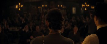 Movie still from “The Immigrant” (2013), directed by James Gray – A woman in a crowd of people in a room; Medium shot, Over the shoulder angle