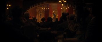 Movie still from “The Immigrant” (2013), directed by James Gray – A group of people sitting in front of a stage; Wide shot, Over the shoulder angle