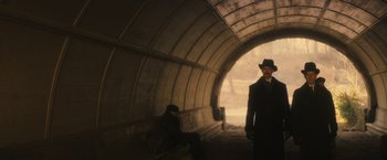 Movie still from “The Immigrant” (2013), directed by James Gray – A man in a suit and hat standing in front of another man in a hat; Wide shot, Low angle