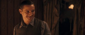 Movie still from “The Immigrant” (2013), directed by James Gray – A man smiling while standing in front of a wooden wall; Close Up shot, Over the shoulder angle