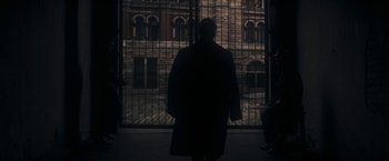 Movie still from “The Immigrant” (2013), directed by James Gray – A person standing in front of an iron gate; Wide shot, Over the shoulder angle