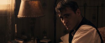 Movie still from “The Immigrant” (2013), directed by James Gray – A man in a suit and tie in front of a lamp; Close Up shot, Over the shoulder angle