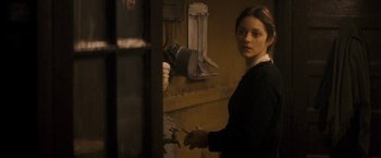 Movie still from “The Immigrant” (2013), directed by James Gray – A young woman holding a knife in a room; Medium shot, Over the shoulder angle