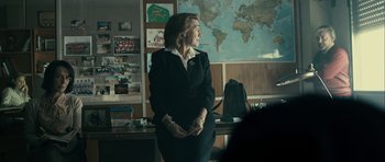 Movie still from “The Imposter” (2012), directed by Bart Layton – A woman sitting in front of a map of the world; Medium shot, Over the shoulder angle