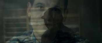 Movie still from “The Imposter” (2012), directed by Bart Layton – A man's face is seen through a window; Close Up shot, Overhead angle