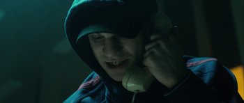 Movie still from “The Imposter” (2012), directed by Bart Layton – A man talking on a phone while wearing a hood; Close Up shot, Low angle