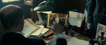 Movie still from “The Imposter” (2012), directed by Bart Layton – A person pointing at a picture of a man in a suit; Medium shot, Over the shoulder angle