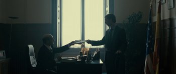 Movie still from “The Imposter” (2012), directed by Bart Layton – Two men are exchanging papers in a dark room; Medium shot, Low angle
