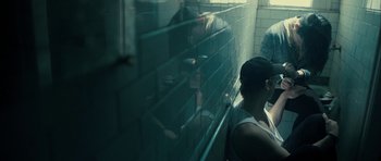 Movie still from “The Imposter” (2012), directed by Bart Layton – A woman standing next to a wall in a bathroom; Medium shot, Over the shoulder angle