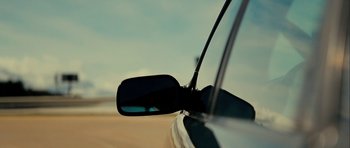 Movie still from “The Imposter” (2012), directed by Bart Layton – A side view mirror of a car on a road; Extreme Close Up shot, Low angle