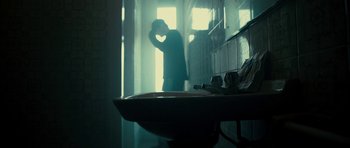 Movie still from “The Imposter” (2012), directed by Bart Layton – A man standing next to a sink in a bathroom; Medium shot, Low angle