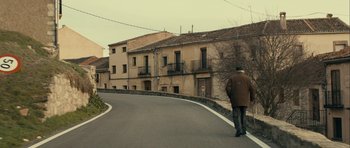 Movie still from “The Imposter” (2012), directed by Bart Layton – A man walking down the street in front of a building; Extreme Wide shot, Low angle