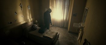 Movie still from “The Imposter” (2012), directed by Bart Layton – A person standing in a room next to a window; Wide shot, High angle
