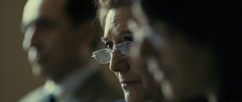 Movie still from “The Imposter” (2012), directed by Bart Layton – An older woman wearing glasses looking out a window; Extreme Close Up shot, Over the shoulder angle