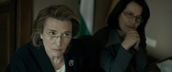 Movie still from “The Imposter” (2012), directed by Bart Layton – A woman wearing glasses and a suit and tie; Close Up shot, Over the shoulder angle