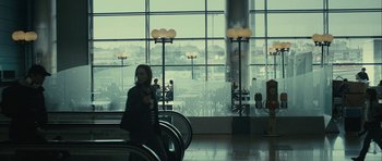 Movie still from “The Imposter” (2012), directed by Bart Layton – A woman is standing in an airport waiting for her luggage; Wide shot, Over the shoulder angle