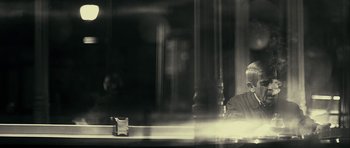 Movie still from “The Imposter” (2012), directed by Bart Layton – A man sitting at a table in front of a window; Close Up shot, Over the shoulder angle