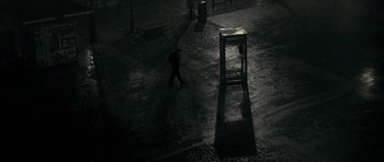 Movie still from “The Imposter” (2012), directed by Bart Layton – A person walking in the dark near a chair; Extreme Wide shot, High angle