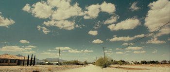 Movie still from “The Imposter” (2012), directed by Bart Layton – A dirt road that has a lot of power lines on the side of the road; Extreme Wide shot, Low angle