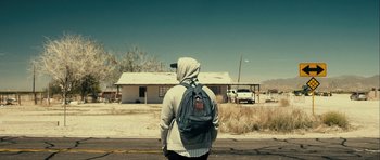 Movie still from “The Imposter” (2012), directed by Bart Layton – A person with a backpack standing on the side of the road; Wide shot, Over the shoulder angle
