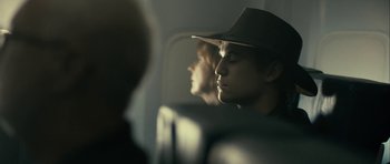 Movie still from “The Imposter” (2012), directed by Bart Layton – A man wearing a hat sitting on a plane looking out the window; Close Up shot, Over the shoulder angle