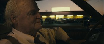 Movie still from “The Imposter” (2012), directed by Bart Layton – An older man sitting in a car looking out the window; Close Up shot, Over the shoulder angle