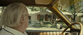 Movie still from “The Imposter” (2012), directed by Bart Layton – An older man sitting in the back seat of a car; Close Up shot, Over the shoulder angle