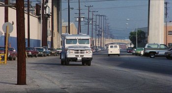 Movie still from “The In-Laws” (1979), directed by Arthur Hiller – A truck driving down a street next to a street light; Extreme Wide shot, Low angle