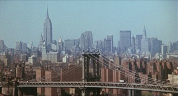 Movie still from “The In-Laws” (1979), directed by Arthur Hiller – A view of a city skyline with a bridge in the foreground; Extreme Wide shot, High angle