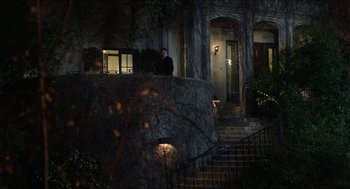 Movie still from “The In-Laws” (1979), directed by Arthur Hiller – A man standing on the steps outside of a house at night; Wide shot, Low angle