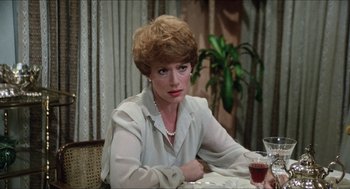 Movie still from “The In-Laws” (1979), directed by Arthur Hiller – A woman sitting at a table with a glass of red wine; Close Up shot, Over the shoulder angle