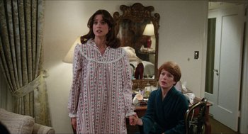 Movie still from “The In-Laws” (1979), directed by Arthur Hiller – Two people in a room holding hands and one of them is wearing a nightgown and the other is wearing pajamas; Medium shot, Over the shoulder angle