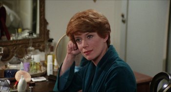 Movie still from “The In-Laws” (1979), directed by Arthur Hiller – A person sitting at a table in a room; Close Up shot, Over the shoulder angle