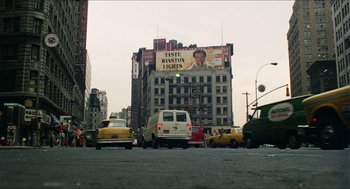 Movie still from “The In-Laws” (1979), directed by Arthur Hiller – A busy city street with cars and a van on the road; Extreme Wide shot, Low angle