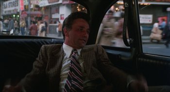 Movie still from “The In-Laws” (1979), directed by Arthur Hiller – A man sitting in the back seat of a car; Medium shot, High angle