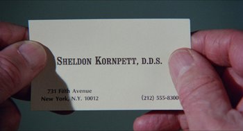 Movie still from “The In-Laws” (1979), directed by Arthur Hiller – A person holding a business card in their hand; Extreme Close Up shot, Overhead angle